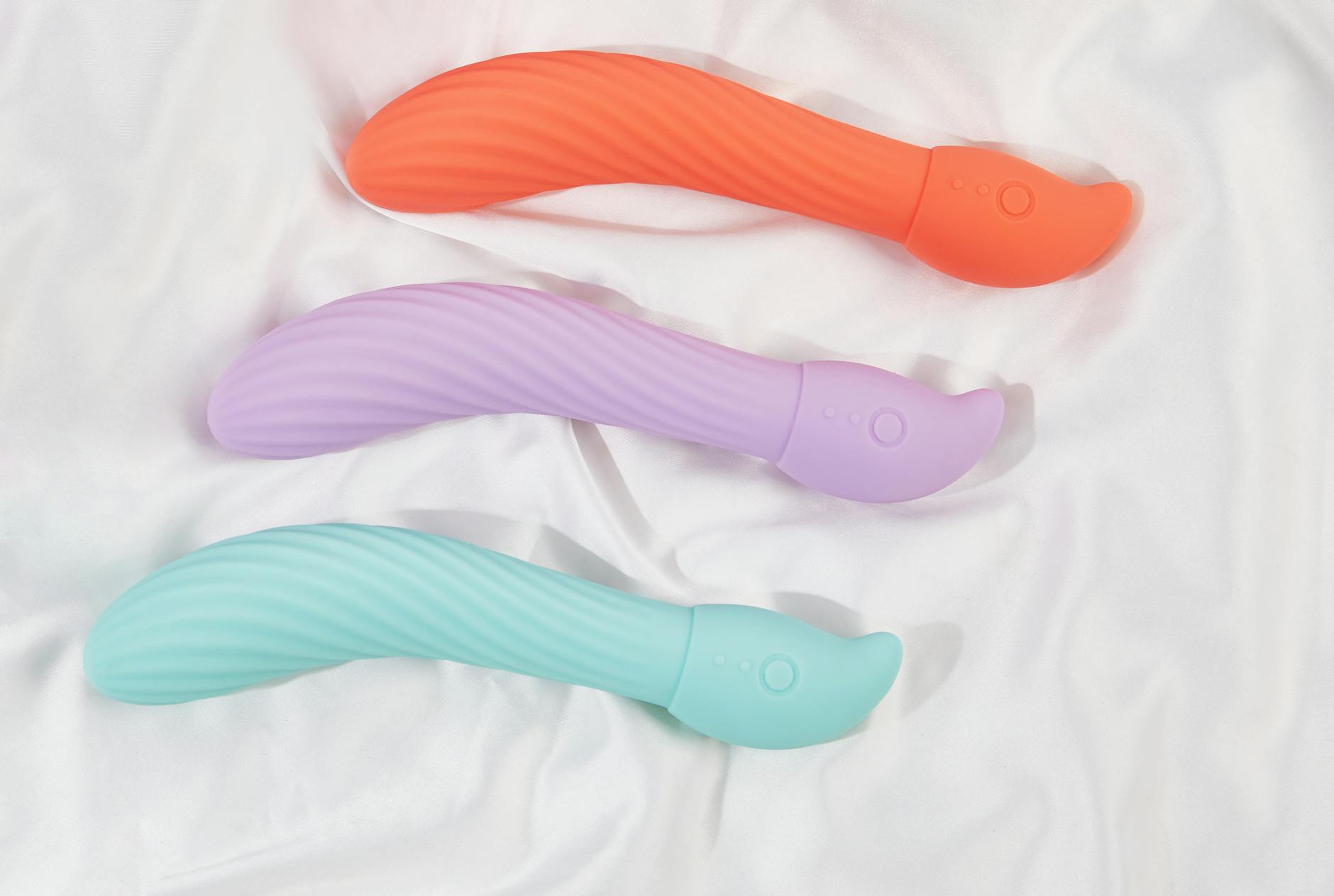 Colorful vibrators arranged on white fabric showing different toy styles and textures