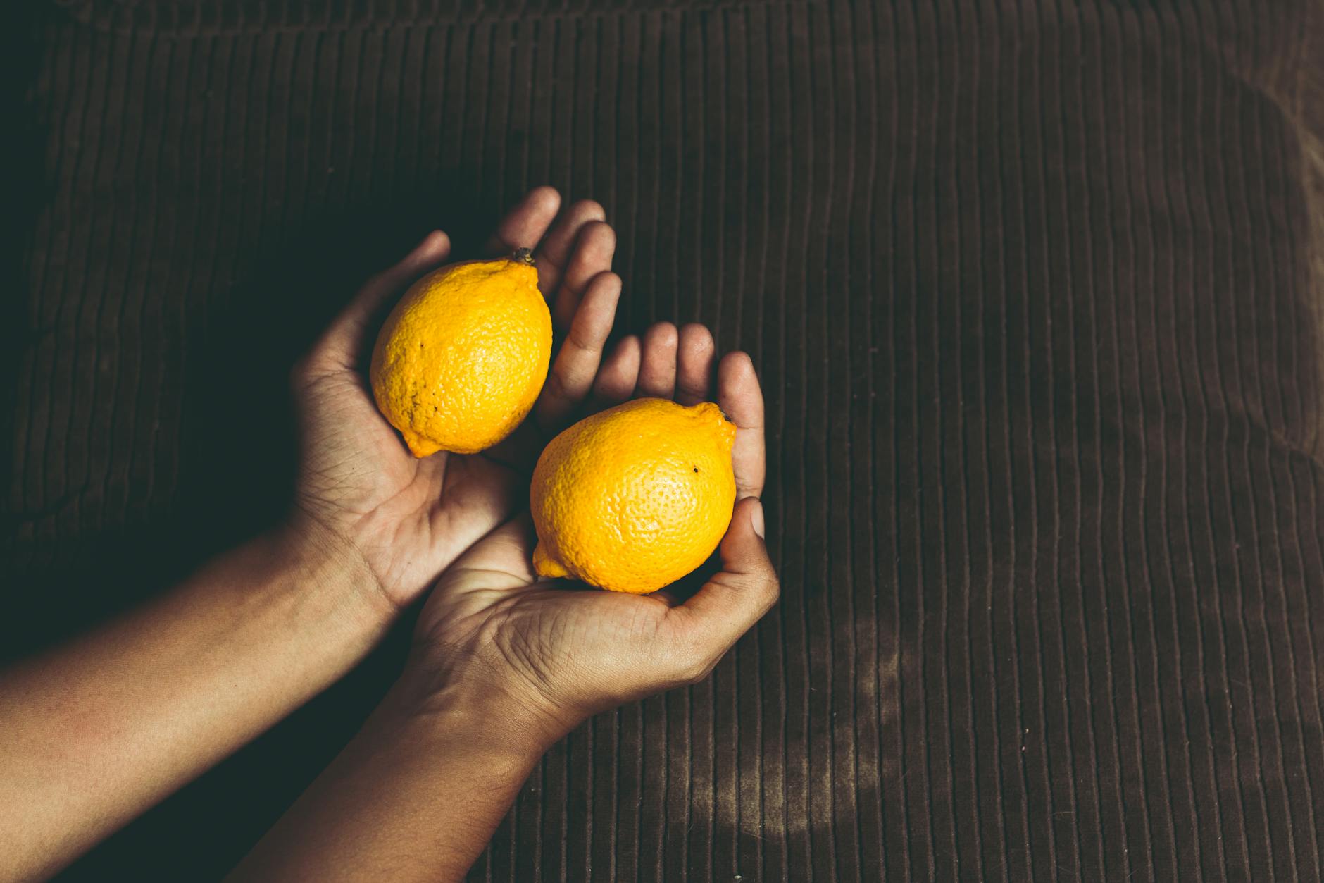 Close-up of two fresh lemons held in hands, representing the Hello Nancy lemon vibrator brand