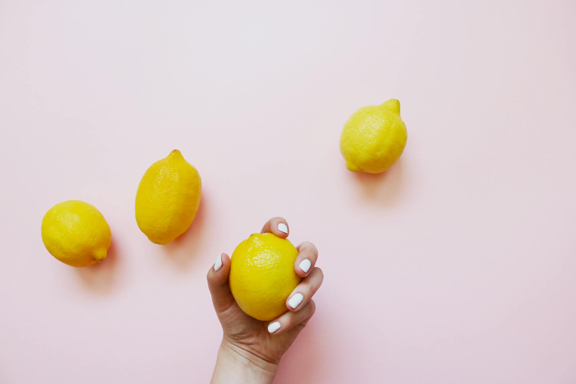 Two hands holding colorful silicone lemon vibrators together against a neutral background
