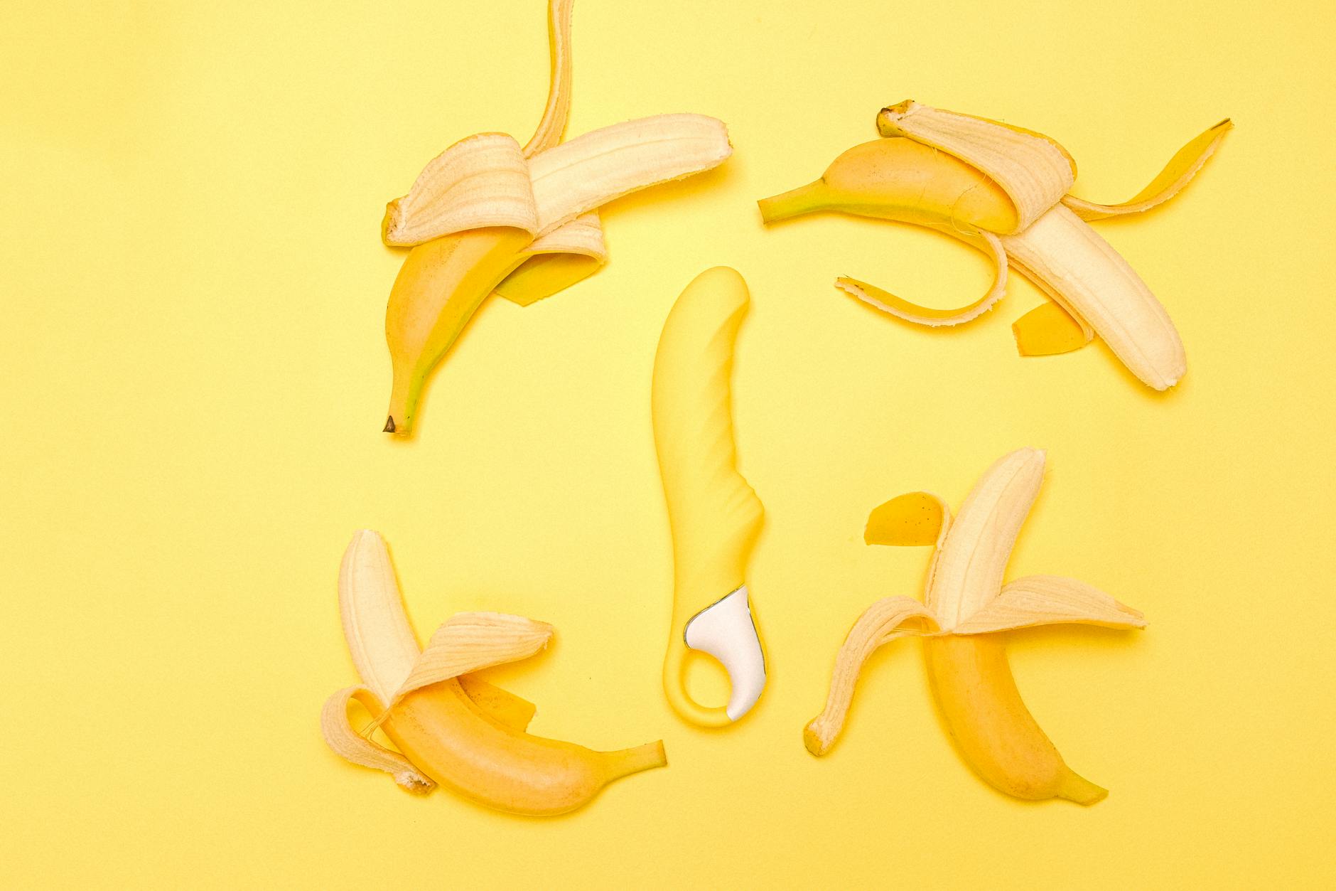 Colorful clitoral vibrators arranged on a bright yellow background, showcasing various shapes designed for different types of stimulation.