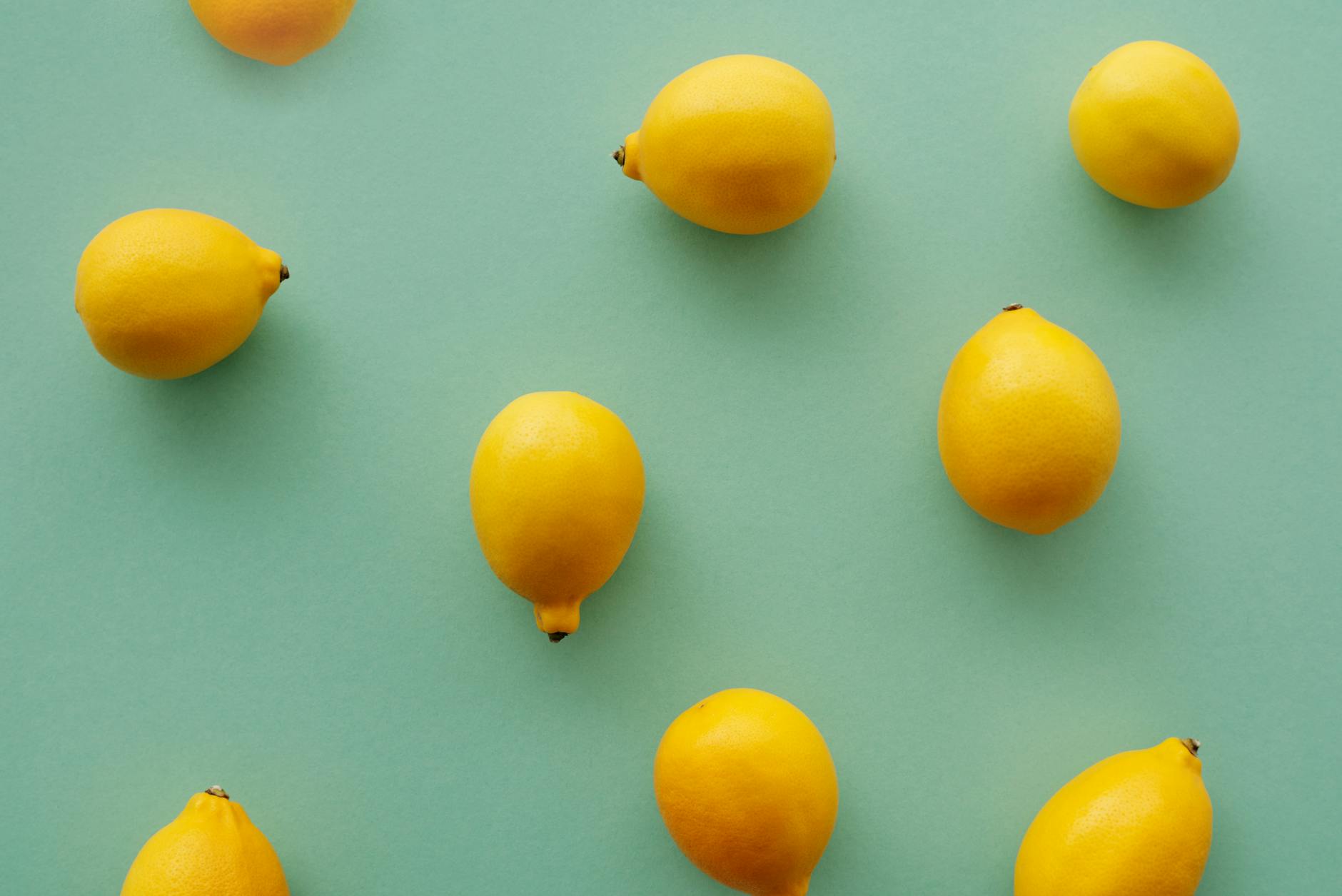 Bright yellow lemons arranged on a pastel green background, symbolizing the refreshed pleasure possible with lemon vibrators after menopause.