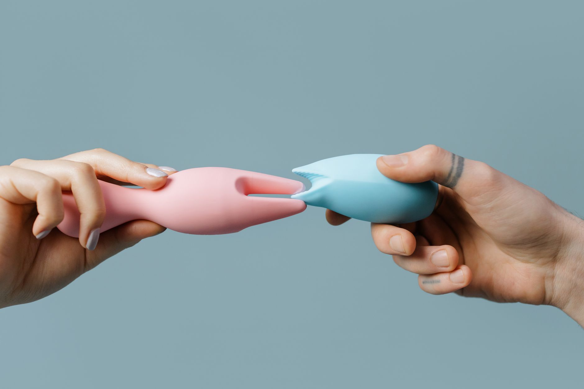 Intimate close-up of hands holding a blue vibrator against a purple background