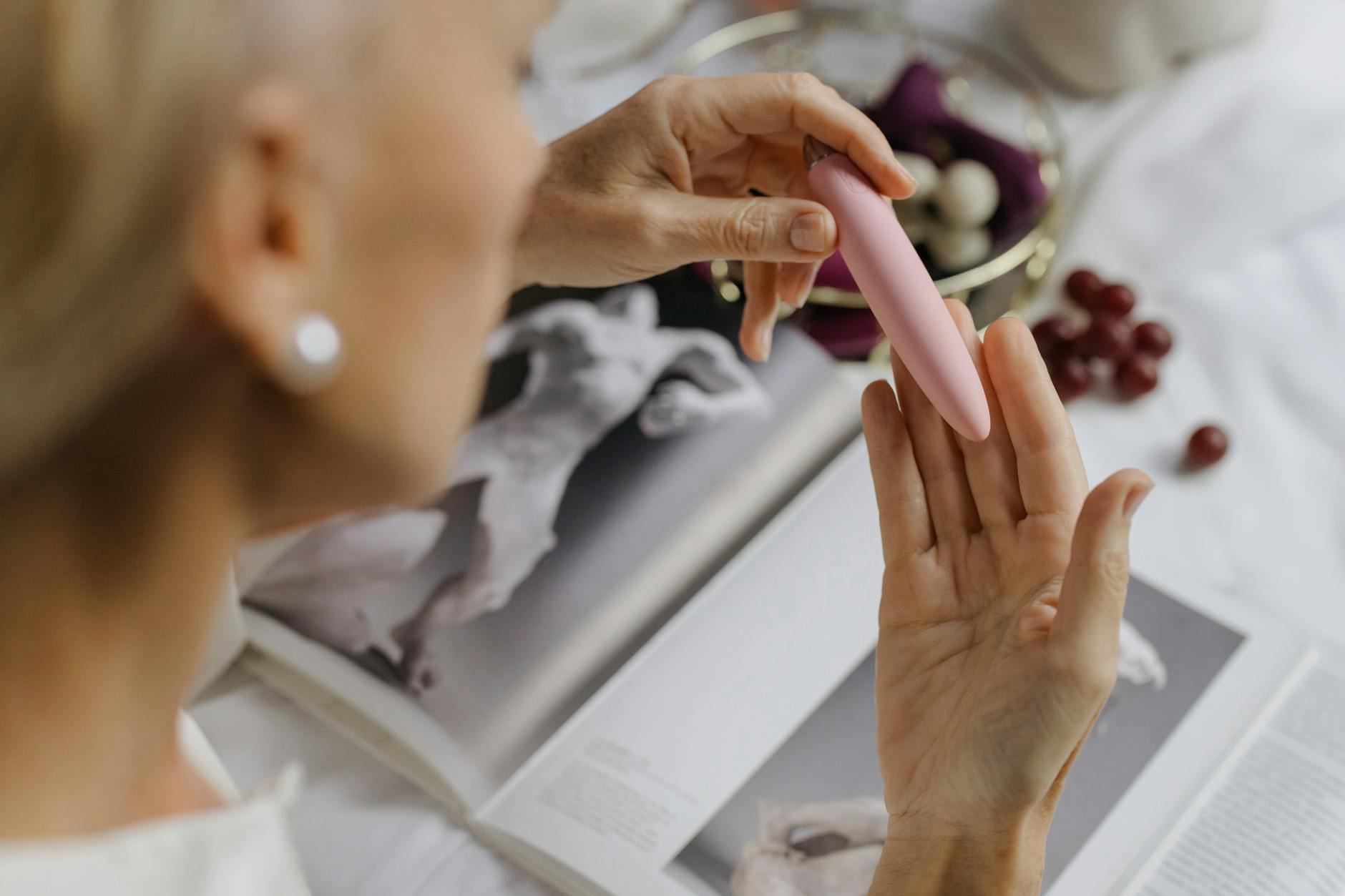 Woman holding blue and pink silicone vibrators in contemplative manner