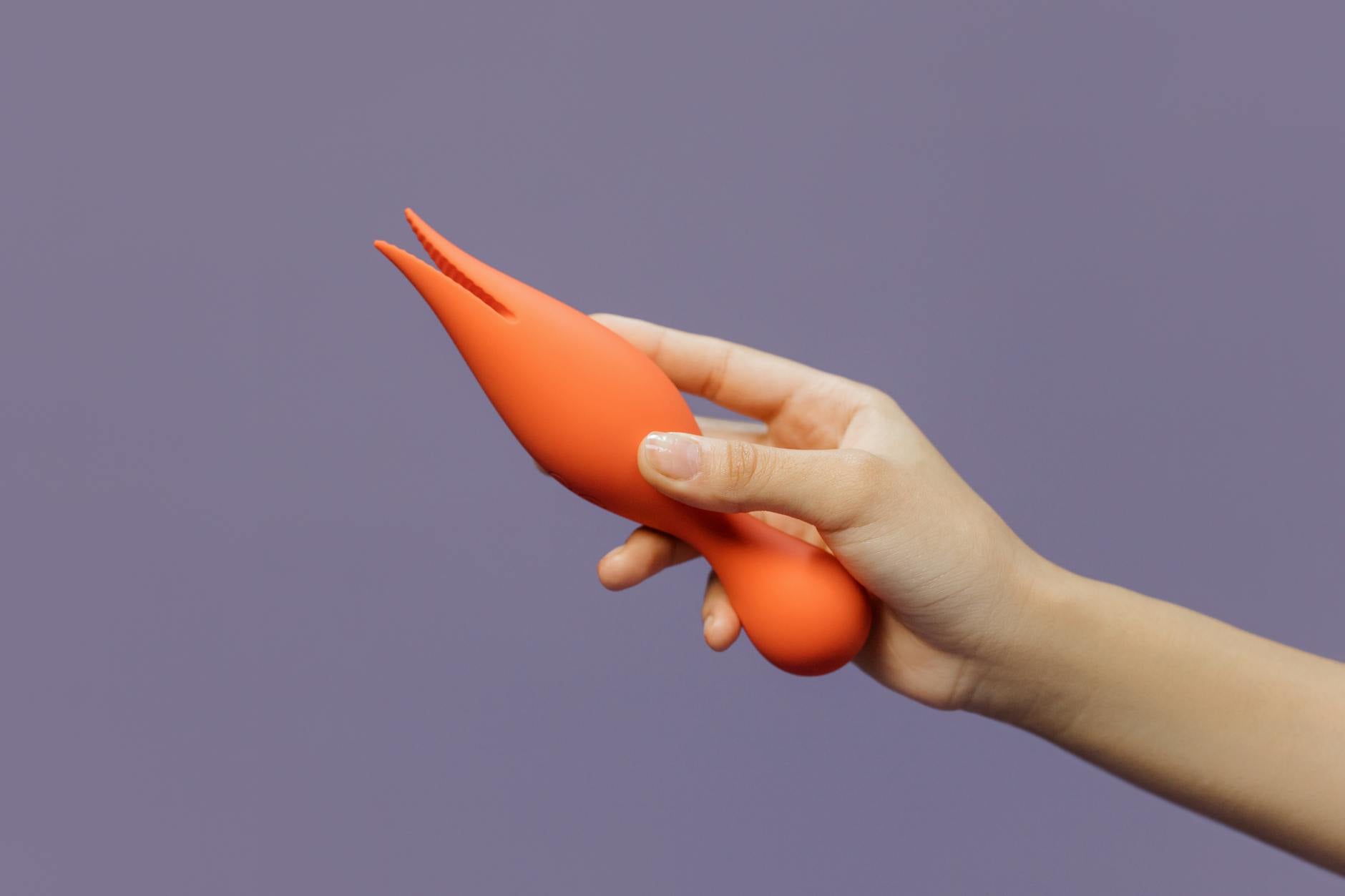 A hand holding a vibrator against a minimalist backdrop, representing modern solo pleasure and self-connection.